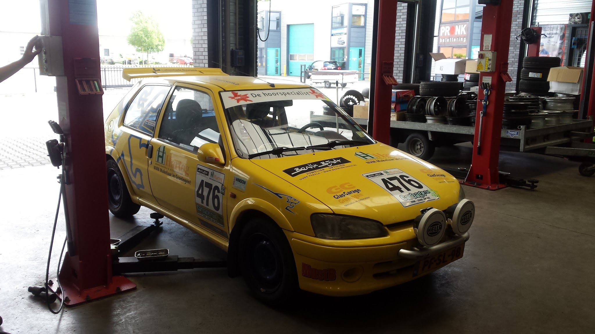 Gele rallyauto met startnummer op de brug in de werkplaats